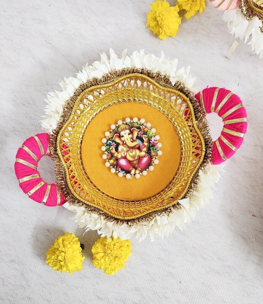 Floral Art presents Decorative plate adorned with a central figure, surrounded by intricate designs and bordered by white flowers, pink and gold accents, and yellow flowers beneath.