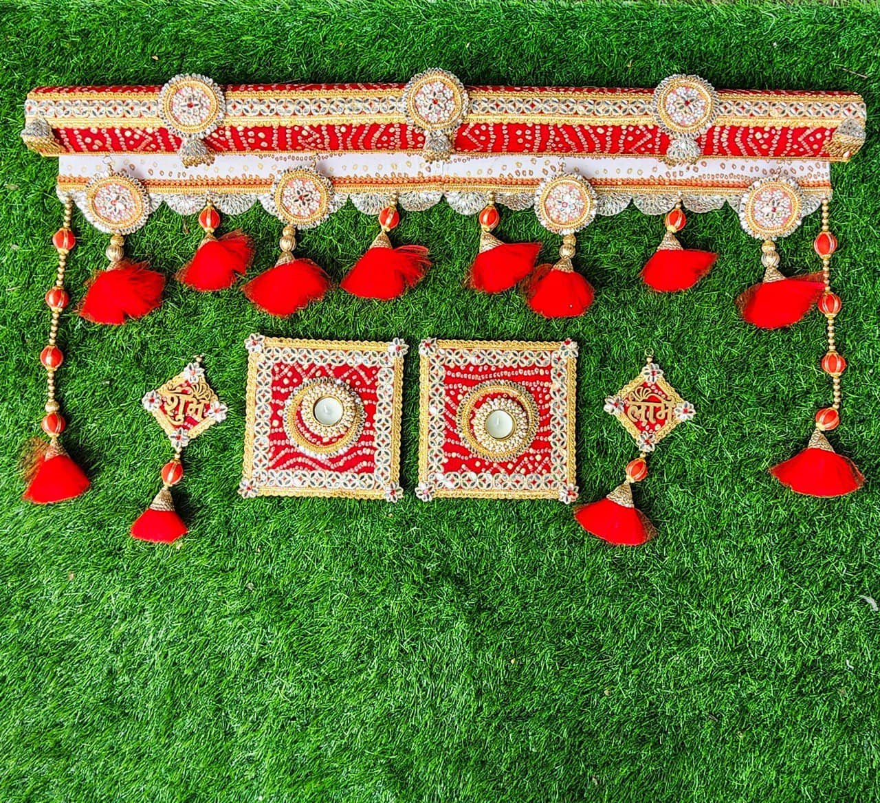 Floral Art presents Intricate red and gold decorative embroidery with tassels and geometric patterns on a green grass background.